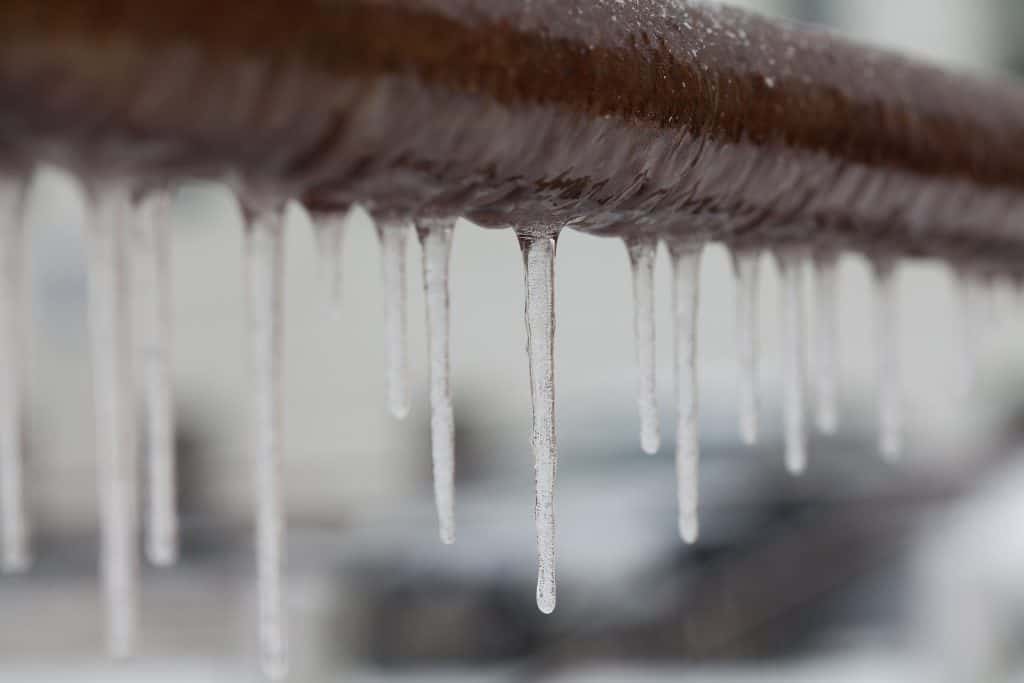 Icicles hanging from a brown pipe. Frozen water and metal surface, winter time concept. selective focus shallow depth of field Fire sprinkler system