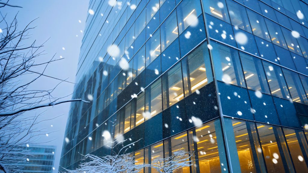 Exterior outdoors outside view of snow falling on tall corporate company glass building window wall architecture. Cold frozen winter weather, modern facade house or home design structure See Less By Nemanja